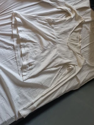 Vit ribbad långärmad topp Odd Molly - Säljer en vit ribbad långärmad topp från Odd Molly med v-ringning. Toppen har en mjuk och stretchig känsla, tillverkad i bomull. Liten Odd Molly-label sitter fastsydd nedtill. Perfekt till jeans eller kjol för en avslappnad look.