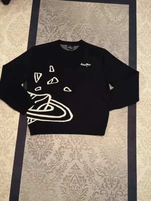 Svart stickad tröja från Broken planet  - Cool svart stickad tröja från André Butik med vita rymdmotiv som planeter, stjärnor och asteroider både fram och bak. Tröjan har rund hals och långa ärmar. Perfekt för dig som gillar unika och grafiska plagg.