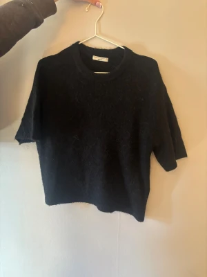 Svart stickad tröja Gina Tricot XS - Mysig svart stickad tröja från Gina Tricot i premiumkvalitet. Tröjan har kortare ärmar och en klassisk rund halsringning. Perfekt för lager-på-lager och enkel att matcha med olika outfits.