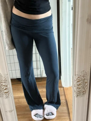Mörkblå utsvängda leggings - Säljer ett par mörkblå leggings med utsvängda ben och bred midjeresår. Mjukt och stretchigt material som sitter skönt på kroppen. Perfekta för en avslappnad och trendig look.