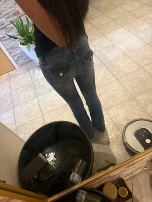 Blå bootcut jeans med slitningar - Säljer ett par blå bootcut jeans med snygga slitningar framtill och klassiska fickor bak. Jeansen har en knappgylf och är tillverkade i denim med lätt stretch. Perfekta för en avslappnad och trendig look.