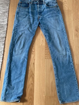 Levi's 501 32/32 - Klassiska raka jeans från Levi's i ljusblå denim. Jeansen har fem fickor, gylf med dragkedja och knapp samt synliga sömmar. Tillverkade i bomull och har en tidlös passform som funkar till många stilar.