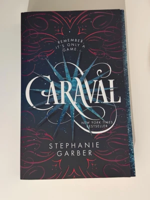 🇬🇧Caraval av Stephanie Garber - Caraval är en fantasyroman på engelska av Stephanie Garber. Omslaget är mörkblått med vita och turkosa detaljer samt röda mönster. Boken är en New York Times bestseller och riktar sig till unga vuxna. Perfekt för dig som gillar magi, mysterier och äventyr. Helt ny skick, aldrig läst OBS!!! Vanlig storlek, inte pocket 
