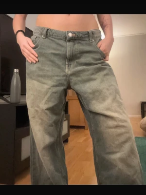 Baggy bershka jeans - Baggy jeans i grått med rak passform och klassisk femficksdesign. Jeansen har en något tvättad look och hög midja. Perfekta för en avslappnad och trendig stil. Materialet är denim.