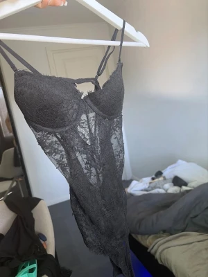 Svart spetsbody med blommönster - Säljer en svart body i transparent spets med blommönster. 75A XS