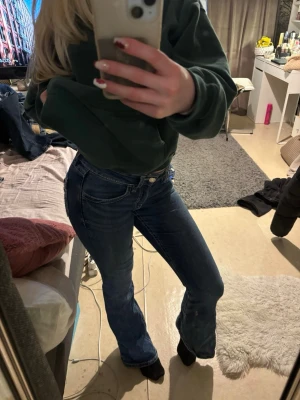 Blå lågmidjade bootcut jeans  - Säljer ett par snygga blå lågmidjade bootcut jeans med coola fickdetaljer bak. Jeansen har låg midja och är i stolek S från Gina tricot. 