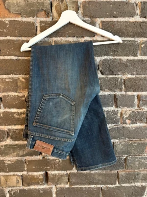 Blå jeans från J.Lindeberg - Snygga blå jeans från J.Lindeberg med klassisk femficksdesign och raka ben. Jeansen har en cool tvättad look med kontrastsömmar. Materialet är denim och passformen är avslappnad. Perfekta för dig som gillar en tidlös och casual stil.