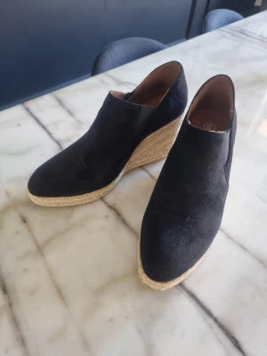Svarta kilklackade pumps med jutesula - Snygga svarta pumps med kilklack och jutesula. Ovandelen är i mockaliknande material.
