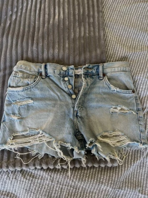 JEANSSHORTS MED SLITNINGAR - Säljer ett par riktigt coola ljusblåa denimshorts från Zara med medel/hög midja och slitningar. Riktigt snygga med en baggy t-shirt till sommaren! 