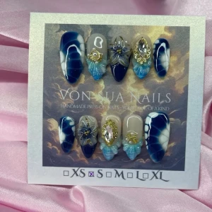 BlueSiren(S);Medium Almond - Unika Handgjorda press-on naglar i blått, vitt och beige med havsinpirerad designe, 3D-dekorationer, guldiga detaljer och stora glittriga stenar. Mix av design och glansig finish, medium almond form. Perfekt för dig som vill sticka ut med unika naglar.