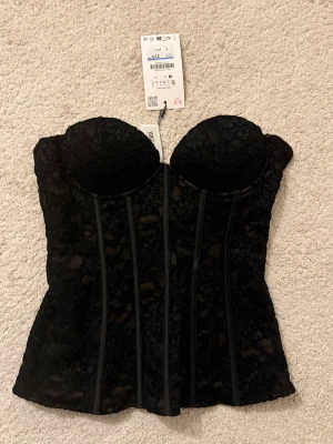 Svart spetskorsett från Zara - Trendig svart korsett från Zara med vacker spets och vadderade kupor. Super fin! 