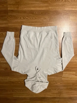 Ljusgrå hoodie med magficka - En stilren ljusgrå hoodie med klassisk magficka och huva med dragsko. Hoodien har ribbade muddar vid ärmslut och nederkant. Perfekt för en avslappnad och bekväm look. Materialet känns mjukt och skönt mot huden.