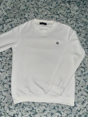 Moncler sweatshirt vit - strl S - Vit sweatshirt från Moncler i storlek S. Klassisk och stilren design med liten logga på bröstet. Väldigt bekväm och lätt att matcha till både vardags- och streetwear-outfits. Använd försiktigt och i mycket bra skick utan fläckar eller hål.  Storlek: S Skick: Mycket bra Färg: Vit Märke: Moncler Passform: Normal