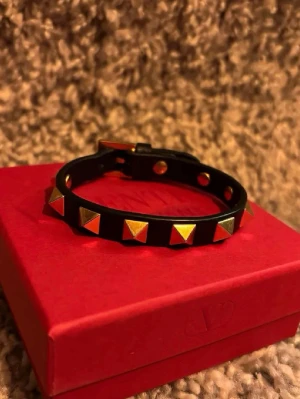 Svart Valentino armband - Svart armband från Valentino Garavani med guldiga  nitar. Armbandet är av läder och är justerbar. Aldrig använt. Mvh NS. OBS: Endast armband ingår!