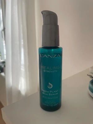 L'ANZA Healing Strength Silk Serum - L'ANZA Healing Strength Neem Plant Silk Serum i en turkos plastflaska med grå pump. Innehåller 100 ml och är ett silkeslent serum för håret med anti-aging egenskaper. Perfekt för att ge glans och styrka till håret.