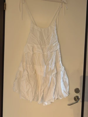 Vit klänning - Säljer en luftig fin vit kortklänning med tunna axelband som knyts. Passar perfekt till sommaren eller som studentklänning! Den har aldrig kommit till användning, där av säljer jag den. Behövs att strykas!