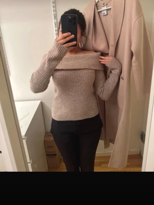 Beige off shoulder ribbstickad tröja - Säljer en beige ribbstickad tröja med off shoulder-design och långa ärmar. Tröjan har en bred krage som går över axlarna och är gjord i ett mjukt stickat material. Perfekt för dig som gillar en stilren och trendig look.