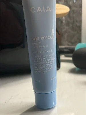 CAIA SOS Rescue Balm 25g - En ljusblå tub med CAIA SOS Rescue Balm, 25g. Innehåller sheasmör och vitamin E, passar alla hudtyper och återfuktar torra partier. Perfekt för att mjuka upp huden och minska torrhet. Smidig att ta med i väskan. Orginal pris: ca 250 (2024s julkalender) mitt pris: 138kr