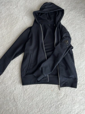 Svart hoodie från Moose Knuckles - Säljer en äkta svart hoodie från Moose Knuckles i storlek M. Bra skick, inga skador.
