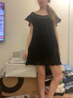 Svart kortklänning med spetsdetaljer - Svart kortklänning med bred spets runt halsen och axlarna. Bra skick storlek S! Kommer inte ihåg vart den är köpt.