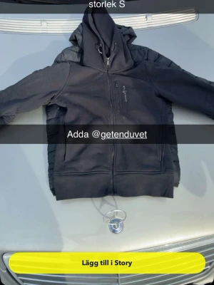 Svart zip hoodie från seil recing  - Säljer en svart hoodie från Peak single Performance med dragkedja framtill och huva. Flat design med diskret logga på bröstet och fickor på sidorna. Perfekt för chill dagar eller när du vill ha en enkel och clean look.