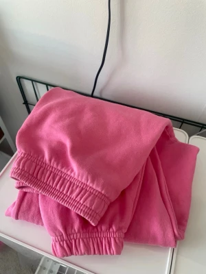 Rosa mjukisbyxor med resår - Säljer ett par sköna rosa mjukisbyxor med resår i midjan och vid bensluten. Perfekta för chill dagar hemma eller när du vill vara aningen extra comfy. Tillverkade i mjukt material som känns nice mot huden. Inga synliga loggor eller märken.