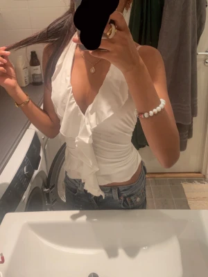 Vit volang topp med v-ringning - Snygg vit topp med djup v-ringning och volangdetaljer framtill. Har använt 3-4 ggr