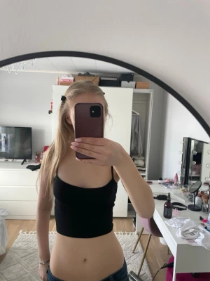 Svart croppad ribbad linnetopp Monki - Säljer en svart croppad linnetopp från Monki i storlek XXS. Toppen är ribbad och ärmlös med smala axelband, perfekt för dig som gillar en enkel och stilren look. Materialet är mjukt och stretchigt, vilket gör den bekväm att bära.