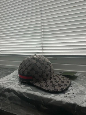 Gucci keps med GG-mönster - Säljer en helt ny snygg Gucci keps i beige och brunt med klassiskt GG-monogram över hela kepsen. På sidan finns en röd och grön rand som ger extra lyxig känsla. Går att beställa också för billigare pris, kontakta mig💫