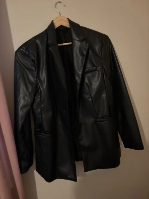 Svart oversized skinnkavaj - Snygg svart skinnkavaj i oversized modell med klassisk krage och tre framfickor.