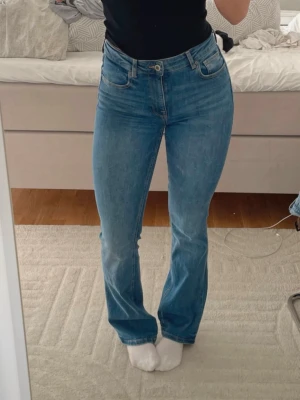 Blå bootcut jeans från Zara - Snygga blå bootcut jeans från Zara med klassisk femficksdesign och hög midja. Jeansen har en lätt utsvängd passform nertill och är tillverkade i denim med en mjuk känsla. Använda kanske 3-4 gånger, passar inte riktigt mig efter dom är högmidjade. Super sköna! 