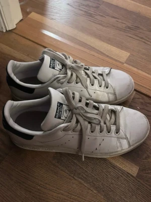 Adidas Stan Smith vita sneakers - Jättefina vita Adidas Stan Smith sneakers med mörkblåa detaljer, har lite slitning (se bild 3) men inget man lägger märke till💗