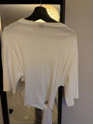 Topp med knyt bak - Säljer denna topp ifrån Gina som har öppen rygg där bak med knyt och tre kvarts armar! Jätte fin men kommer ej till användning. Storlek M 