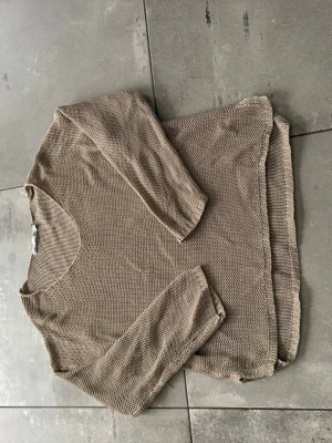 Beige stickad tröja från 157 - Stickad tröja i beige från 157 med rund halsringning. Tröjan har en avslappnad passform och är gjord i ett grovt stickat material som ger en cool och enkel look. Perfekt att matcha med jeans eller kjol.