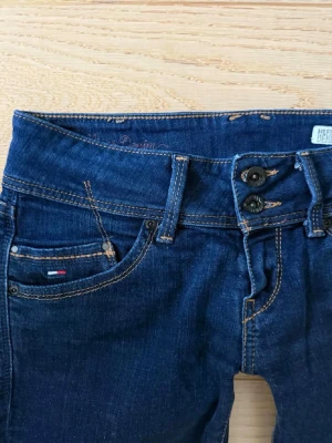 Mörkblåa Tommy Hilfiger jeans - Jag säljer ett par low waist bootcut jeans från Tommy Hilfiger för 500kr priset kan även diskuteras. Dem är i storlek W29 men i en mindre modell, dem sitter som S-M.