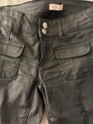 Svarta bootcut-jeans från Nelly - Snygga svarta skinnbyxor/jeans från Nelly. De finns inte längre att köpa! Ass snygga och sitter jätte fint! Jätte fint material!