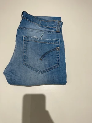 Dondup jeans - Säljer ett par ljusblå slim fit jeans med klassisk femficksdesign och normal midja. Jeansen har en snygg tvätt och är tillverkade i denim med lite stretch för extra komfort. Perfekta för en avslappnad och trendig look. Modellen är 187 och väger 70kg. Vid funderingar är det bara att skriva!