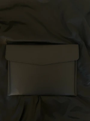 Dator fodral i läder imitation - Stilrent datorfodral tillverkat av veganskt läder i vattentätt material. Fodralet stängs med knapp. Fodralet skyddar din dator effektivt samtidigt som det ger din outfit en extra touch. ⚜️ Storlek: 34 × 25 cm –  Innifrån 33 x 24 📦  