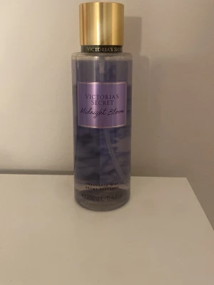 Victoria's Secret Midnight Bloom mist - Fräsch body mist från Victoria's Secret i doften Midnight Bloom. Flaskan är genomskinlig med lila vätska och har ett elegant guldigt lock. Rymmer 250 ml och är perfekt att ha med i väskan för en snabb uppfräschning. Använd fåtal gånger.