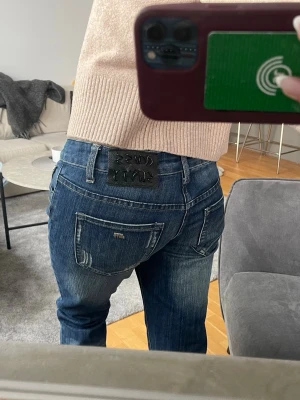 Lowrise jeans från miss sixty - Snygga mörkblå jeans från miss sixty med klassisk femficksmodell och slitningar på bakfickorna. Jeansen har en bootcut passform och tydliga kontrastsömmar. Perfekta för en snygg och trendig look.