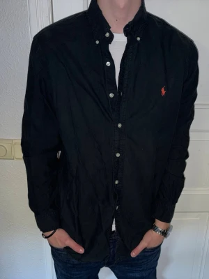 Svart skjorta från Ralph Lauren - Svart skjorta från Ralph Lauren i storlek L. Fint skick till ett bra pris. Nypris: 1995kr. Mitt pris: 349kr. Vid frågor eller funderingar, tveka inte att höra av dig.