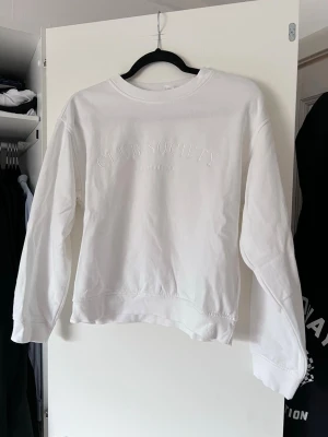 Vit sweatshirt från H&M, storlek XS - Säljer en stilren vit sweatshirt från Club Society med broderad text på framsidan. Tröjan har långa ärmar och ribbade muddar vid ärmslut och nederkant. Perfekt för en avslappnad look. Finns ett litet märke på baksidan av vänster axel!