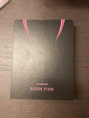 BLACKPINK Born Pink bok - Säljer en snygg bok med titeln 'Born Pink' från BLACKPINK. Omslaget är svart med rosa detaljer och text, och boken har en modern och stilren design. Perfekt för dig som gillar K-pop och vill ha något unikt i bokhyllan.