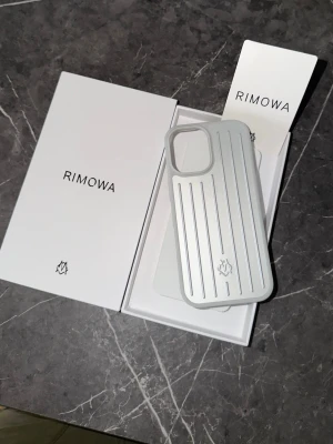 Silverfärgat mobilskal från Rimowa iphone16pro - Snyggt och stilrent mobilskal från Rimowa i silverfärgad aluminium med klassiska räfflade linjer. Skalet har en modern design och är tillverkat i tåligt material som ger exklusiv känsla. Perfekt för dig som vill ha ett premiumskal till din mobil.