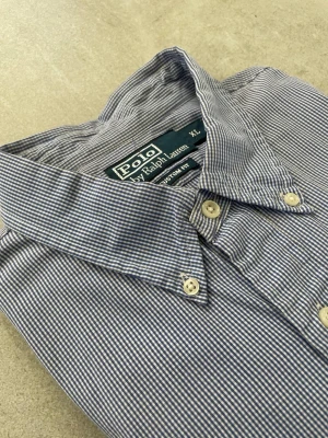 Blårandig skjorta från Polo Ralph Lauren - Klassisk blårandig skjorta från Polo Ralph Lauren i bomull. Skjortan har lång ärm, knappar framtill och button-down krage. Diskret logga broderad på bröstet. Perfekt för en clean och stilren look.