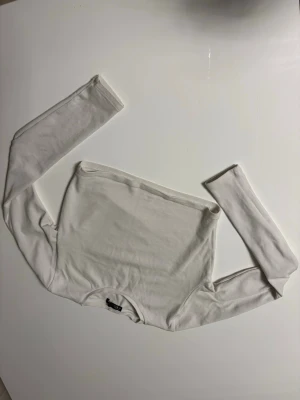 Vit långärmad topp från Zara - Säljer en enkel och stilren vit långärmad topp från Zara. Modellen är tight och har rund halsringning. Tillverkad i mjukt och stretchigt material som känns skönt mot huden. Perfekt att matcha med jeans eller kjol för en clean look.