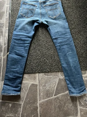 Tiger of sweden, Blå slim fit jeans  - Säljer ett par klassiska blå jeans i slim fit-modell med raka ben och snygga bakfickor. Användt kanske 5 gånger. Jeansen har en tidlös tvätt och kontrastsömmar. Perfekta till vardagslooken och tillverkade i mjukt denimtyg för skön känsla.