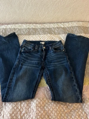 Mörkblåa bootcut low waist jeans  - Dessa par jeans är från ginatricot. Tror inte dom finns kvar längre . Dom är i storlek 170 och är lågmidjade. Dom har broderade mönster på fickorna. Använt några ggr och som man ser på bilden är dom lite slitna på bara ena sidan av längden vid fötterna . Ganska stretchiga utav sig och har ett ganska skönt material . 💞