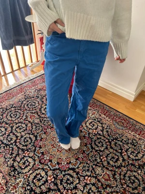 Blå cargobyxor med raka ben - Säljer ett par blå jeans med avslappnad passform och raka ben. Byxorna är tillverkade i ett mjukt bomullstyg. Perfekta för en chill och trendig look.