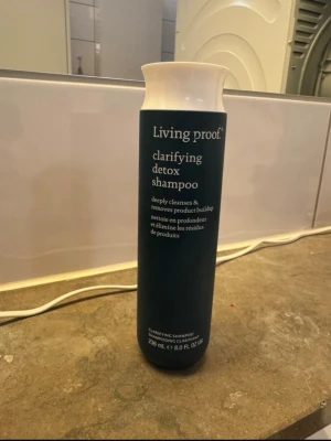 Living Proof detoxschampo 236 ml - Clarifying detox shampoo från Living Proof som djuprengör håret och tar bort produktrester. Flaskan är mörkgrön med vit text och har en stilren, cylindrisk form. Innehåller 236 ml och passar dig som vill ha ett fräscht och rent hår.